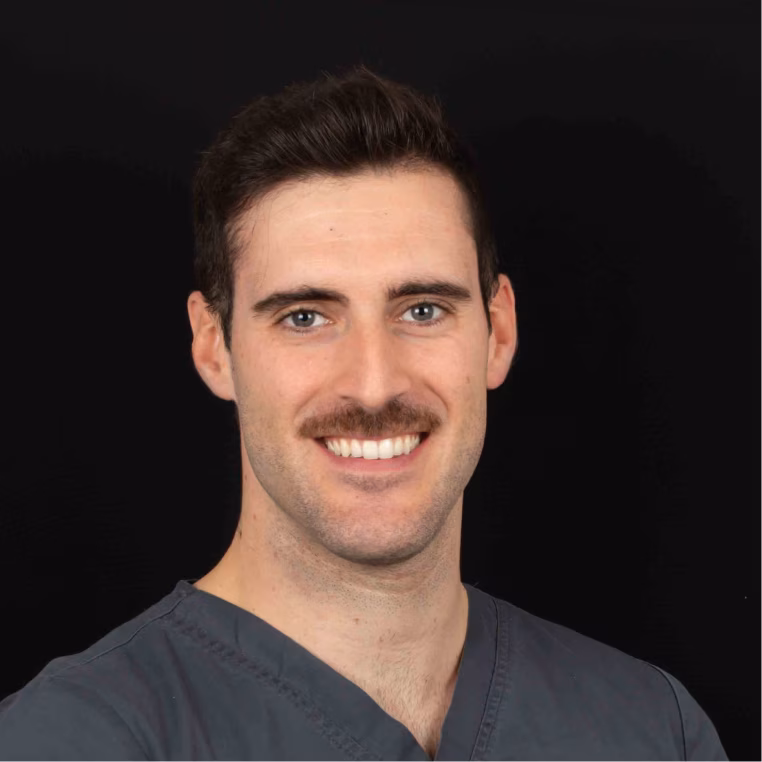 Smiling male dentist in blue scrubs with a stethoscope