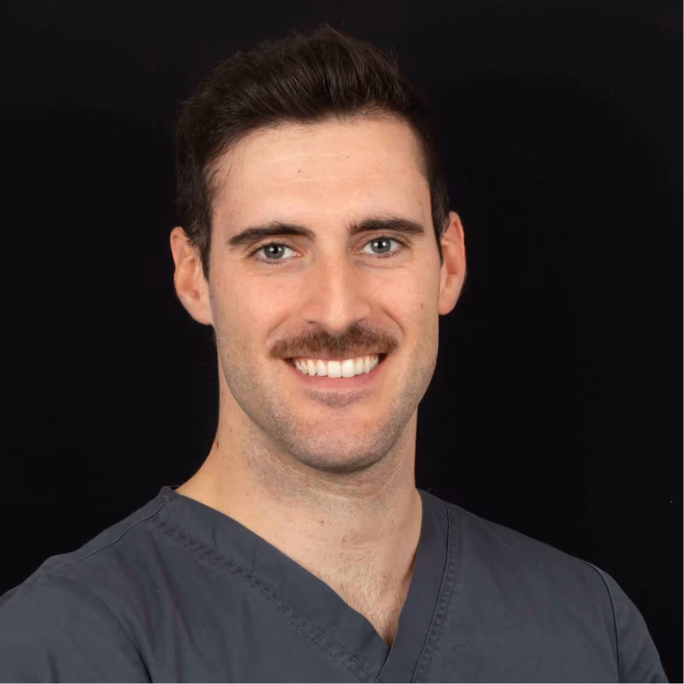 Dr. Name1, smiling dentist in scrubs
